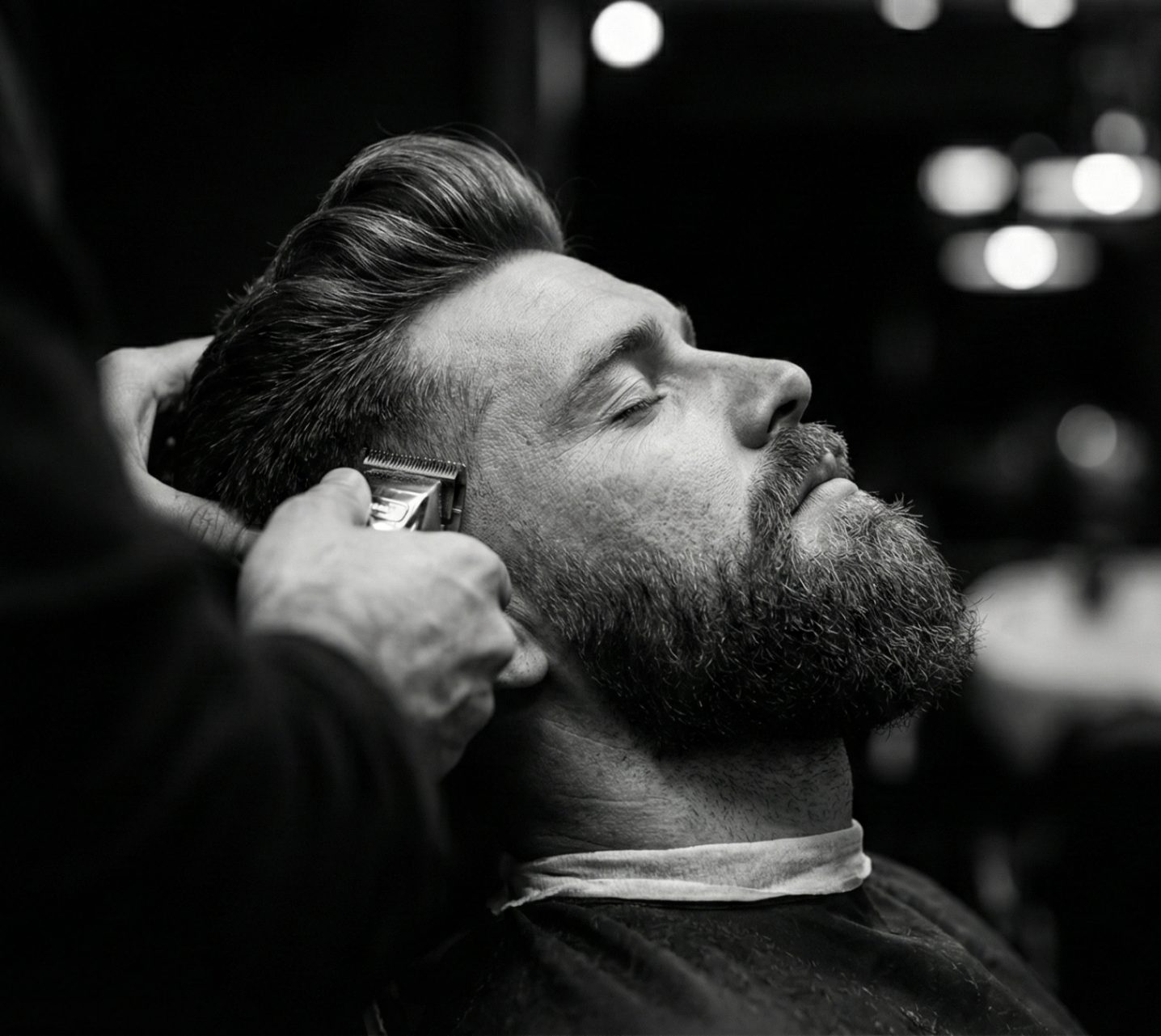 Barber detailing a bearded client's fade with a trimmer